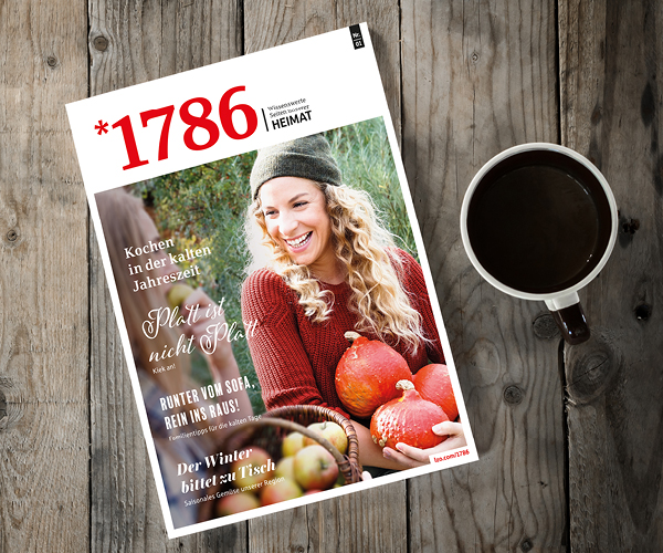 Eine Zeitschrift mit einer lächelnden Frau, die Kürbisse auf dem Titelbild hält, liegt auf einem Holztisch neben einer Tasse Kaffee. Die Zeitschrift enthält Herbst- und Winterthemen in deutscher Sprache, mit der auffälligen Nummer 1786 am oberen Rand.