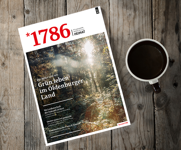 Das Online Magazin *1786 zeigt ein sonnendurchflutetes Waldcover mit deutschem Text, das elegant auf einem rustikalen Holztisch neben einer Tasse schwarzen Kaffees von oben betrachtet liegt.