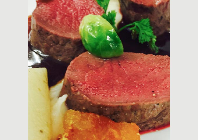 Scheiben vom Rinderfilet mit brauner Soße, garniert mit Rosenkohl, frischen Kräutern, weißem Wurzelgemüse und einem goldgelben, knusprigen Stück auf einem weißen Teller - perfekt zu Ihren Lieblings-Brotbacken-Rezepten.