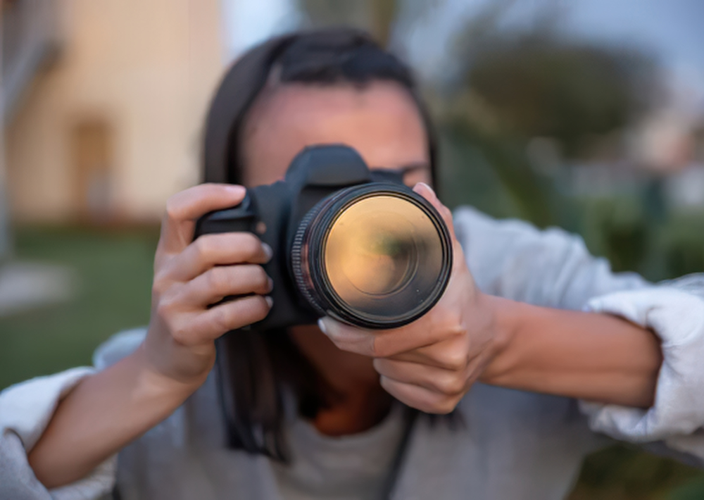 Eine Person hält eine DSLR-Kamera vor ihr Gesicht, um ein Foto für den WirWunder-Fotowettbewerb aufzunehmen.